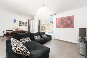 ein Wohnzimmer mit einem schwarzen Sofa und einem TV in der Unterkunft Domus Genti in Son Serra de Marina