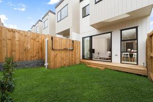 a backyard with a wooden fence and green grass at Te Atatu Cozy Brand New Townhouse 5 in Auckland