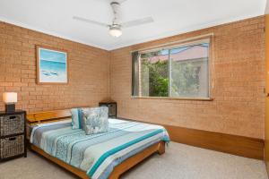 a bedroom with a bed and a brick wall at 1 In Bruns in Brunswick Heads