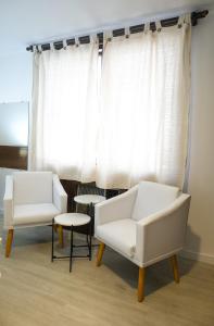 dwa białe krzesła i stół przed oknem w obiekcie Edifício Flat Hotel Congonhas w São Paulo