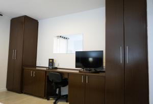 un ufficio con scrivania, TV e armadi di Edifício Flat Hotel Congonhas a San Paolo