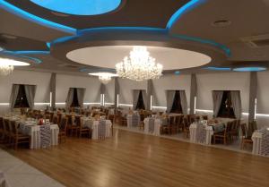 une salle de banquet avec des tables, des chaises et un lustre dans l'établissement Hotel i Restauracja Borowianka, à Ostrów Wielkopolski