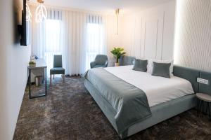 um quarto com uma cama grande, uma secretária e cadeiras em ALIVE HOTEL em Oradea