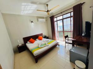 um quarto com uma cama, uma secretária e uma janela em Lafala Hotel & Service Apartment em Colombo