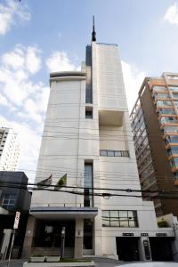 Edifício Flat Hotel Congonhas في ساو باولو: مبنى ابيض طويل عليه اعلامين
