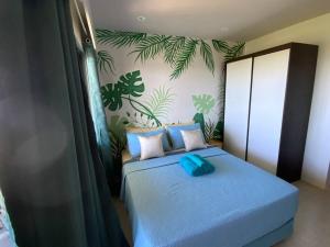 a bedroom with a blue bed with plants on the wall at Ma Roberta - Tambuli Resort with fast Wifi 16 Floor Studio Type in Lapu Lapu City