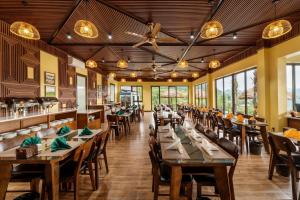 un restaurante con mesas y sillas de madera y ventanas en Central hills Puluong resort en Hương Bá Thước