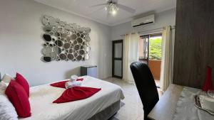 een slaapkamer met een bed met rode kussens en een tafel bij Angelshof Self Catering Guesthouse in Windhoek