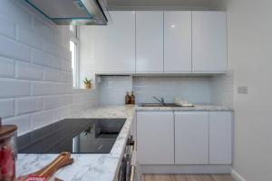 una cocina blanca con armarios blancos y fregadero en Gipsy Cottage with Sunny Garden and Conservatory, en West Dulwich