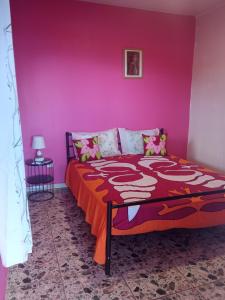 een slaapkamer met een bed met een roze muur bij CHEZ ALIZHIA in Nuku Hiva