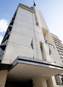 Un palazzo alto e bianco con due bandiere sopra. di Edifício Flat Hotel Congonhas a San Paolo