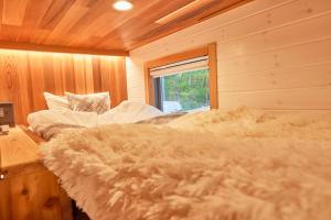 a bedroom with a bed in a wooden room at サウナ・ジャグジー・完全貸し切りという贅沢　大人の秘密基地　Tiny Cabin TATEGU#02 in Miyota