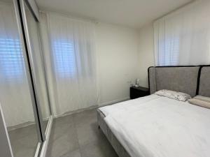 een witte slaapkamer met een bed en een raam bij SVW Apartment on the Beach in Netanya