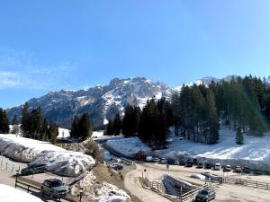 a snow covered mountain with cars parked in a parking lot at Trilocale Ville Golf 35 in Madonna di Campiglio