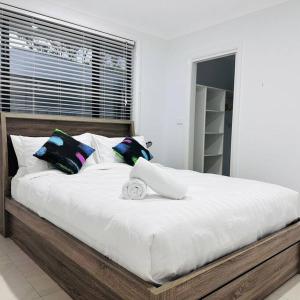 アーミデールにあるHouse on New England Hwyのベッドルーム(大きな白いベッド、カラフルな枕付)