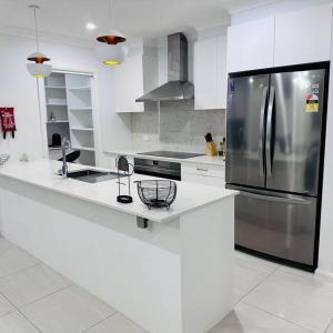 アーミデールにあるHouse on New England Hwyの白いキッチン(ステンレス製の冷蔵庫付)