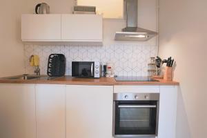 a kitchen with white cabinets and a microwave at Évasion Pro & Fun à Saint-Étienne - Proche HPL in Saint-Étienne