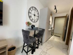 Zimmer mit einem Tisch, 2 Stühlen und einer Uhr in der Unterkunft Hovah Luxury Suite in Accra
