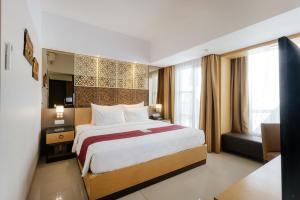 a hotel room with a large bed and a couch at Horison Ultima Seminyak Bali - CHSE Certified in Seminyak