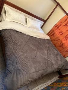 1 cama con edredón marrón y almohadas en Drish Haven en Nairobi