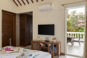 una camera con letto, TV e patio di Villa Hestia-3bed villa in Assagao By Masaya Stays a Verla