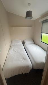 two beds in a small room with a window at 238 Arran View, Craig Tara Holiday Park in Ayr