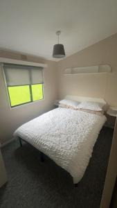 a bedroom with a white bed with a window at 238 Arran View, Craig Tara Holiday Park in Ayr