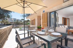 a dining table with an umbrella on a patio at Villa Canta in Playa de Muro