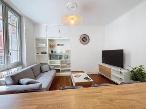 ein Wohnzimmer mit einem Sofa und einem TV in der Unterkunft Concorde - Sublime T3 - Terrasse in Toulouse