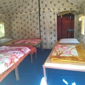 ナイニタールにあるGREEN VALLEY CAMPING & ADVENTUREのテント内のベッド2台が備わる部屋