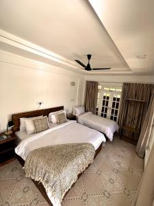 a bedroom with two beds and a ceiling fan at Twin Palms Surfhouse in Thulusdhoo
