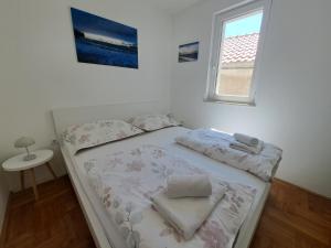 a bed with two towels and a window in a room at Apartment Primosten Adiomare in Primošten +38 photos