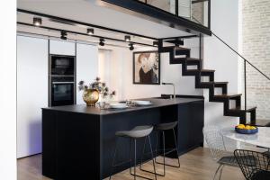 een keuken met een zwart eiland met krukken bij Magno Apartments Sepúlveda in Sevilla