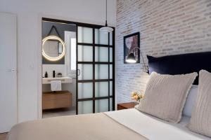 um quarto com uma cama branca e uma parede de tijolos em Magno Apartments Sepúlveda em Sevilha
