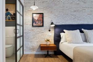 um quarto com uma cama azul e uma parede de tijolos em Magno Apartments Sepúlveda em Sevilha