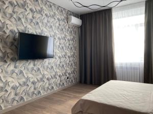 ein Schlafzimmer mit einem Flachbildfernseher an der Wand in der Unterkunft Alpamys Premium центр города in Qostanai