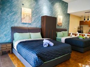 a bedroom with two beds and a blue wall at Regency Tanjung Tuan Beach PD by Idealhub in Port Dickson