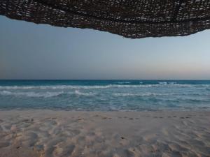 a view of the ocean from under a beach umbrella at Beachfront Villa 3bedrooms+3bathrooms in El Alamein