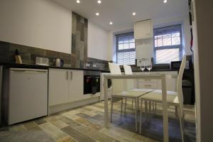 a kitchen with white cabinets and a table and chairs at The Castle Lodge in Tredegar