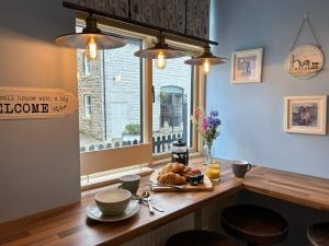 une table avec une assiette de nourriture et une fenêtre dans l'établissement Beautiful 2-Bed Cottage in Heysham Village, à Heysham
