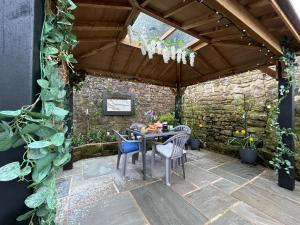 a patio with a table and chairs and a stone wall at Beautiful 2-Bed Cottage in Heysham Village in Heysham