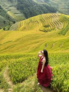 Una mujer con un vestido rojo parada en un campo en See bungalow, en Mù Cang Chải