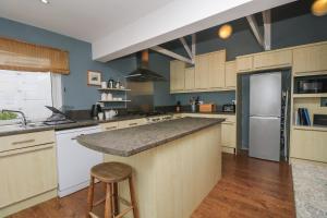a large kitchen with a counter and a refrigerator at Incline Cottage in Portreath