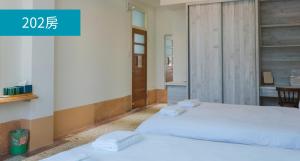 Habitación con 2 camas blancas y escritorio. en Romance Guest House, en Dalin