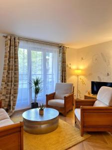 een woonkamer met een bank, stoelen en een tafel bij Appart chaleureux et calme près de PARIS et MÉTRO in Asnières-sur-Seine