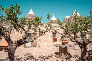 a stone building with two trees in front of it at Trulli Beauty Romantic ALCOVA con piscina in Locorotondo
