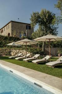 eine Gruppe von Stühlen und Sonnenschirmen neben einem Pool in der Unterkunft Wine Resort Campacci in San Gusmè