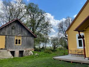 a barn with a porch next to a house at Mazelejas muižiņa in Vircava