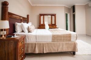 1 dormitorio con 1 cama grande y vestidor de madera en Fatmols City Hotel, en Ndola