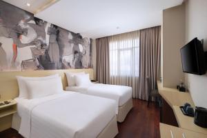 um quarto de hotel com duas camas e uma televisão em Four Star by Trans Hotel em Sanur